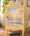 A small yellow cabinet with a large door panel showing an ocean sunset decoupage, styled in a bright room with books, a plant, and woven baskets. Label reads "Digital Rendering for Inspiration. Scale and sizing are approximate."