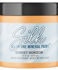A jar of Silk All-In-One Mineral Paint in the shade Sunset Horizon, featuring an orange paint jar with a black lid and a light blue label.