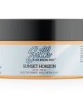 A jar of Silk Sunset Horizon built-in primer top coat mineral paint, featuring a black lid and a white label with orange accents, on a solid white background.