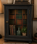A dark rustic bookcase cabinet with a glass door, styled with vintage books, a small potted plant, and a glass bottle on a wooden table, flanked by a lamp and a clock.