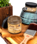 Van Dyke Brown Glaze jar, brush, and decorative items on a wooden surface