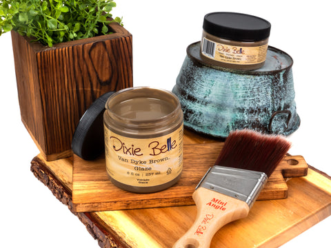 Van Dyke Brown Glaze jar, brush, and decorative items on a wooden surface