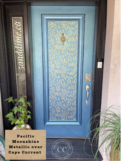 A front door painted in a metallic blue finish with a lighter blue leaf pattern across the center panel. The door has a brass knocker, silver handle, and lockset.