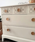 Belles and Whistles Buffalo Check - Stencil provides an extra decorative touch to any project!
A cream colored dresser with the first row of 3 drawers using the Buffalo Check - Stencil with a gray tone and wood hardware.