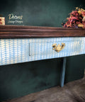 Belles and Whistles Cozy Sweater - Stencil provides an extra decorative touch to any project! A desk that has a dark wooden top and a blue base with one drawers. The desk features the cozy sweater stencil in white on the front and the drawer.