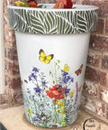 Belles and Whistles Enchanted Garden - Stencil provides an extra decorative touch to any project! White painted pot with the Wildflowers & Butterflies rub on furniture transfer applied to the base and body. Enchanted Garden Stencil applied on the rim of the pot in Deep Woods Moonshine Metallics paint.
