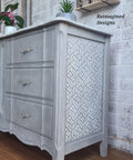 Belles and Whistles Enchanted Garden - Stencil provides an extra decorative touch to any project! Gray painted dresser makeover with one of the Enchanted Garden designs stenciled on the side in white. Staged on a wood floor with a white brick wall in the background.