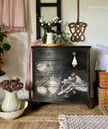Belles and Whistles Floral Ballerina - A1 Rice Decoupage Paper is a simple way to visually enhance any surface of your project!
Black dresser with bronze hardware using the Floral Ballerina - A1 Rice Decoupage Paper on the last three drawers of piece . Staged with a tassel hanging off the top drawer.