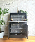 Belles and Whistles Greek Key - Stencil provides an extra decorative touch to any project! Black painted Bar cabinet staged with cabinet open with Greek Key - Stencil inside of piece. Staged with many wine glasses inside of furniture, and greenery staged on top of piece.