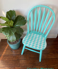 Belles and Whistles Harlequin - Stencil provides an extra decorative touch to any project!
This is a spindle chair painted turquoise.   There is a Harlequin stencil on the seat of the chair.  The colors are turquoise and white.  To the left of the chair is a potted plant.  It all rests on a slated, dark wood floor and a white wall behind.