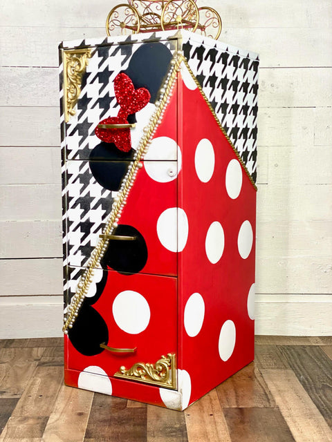 Belles and Whistles Houndstooth - Stencil provides an extra decorative touch to any project!
A file cabinet with half diagonally the cabinet in red with white polka dots and black mouse ears, on the other side is a white base with black Houndstooth - Stencil on top with black mouse ears with a red bow. In Between the two sides is a gold separator.