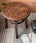 Belles and Whistles Leaf Me Alone - Stencil provides an extra decorative touch to any project! Dark wooden stool with the Leaf Me Alone stencil applied on the seat in dark brown. Staged on a white and gray rug with stacks of books around it.