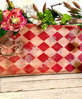 Belles and Whistles Roses - Silkscreen Stencil provides an extra decorative touch to any project! A leather case with a red diamond stencil on the front and top with the rose stencil painted lightly in white. The case is staged with flowers on top.