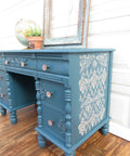 Blue painted desk with wood details on the drawers. Royal Damask stencil has been applied on the side of the desk.