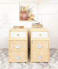 Yellow and white painted cabinets with white handles. The Royal Damask stencil has been applied on the front of the drawers in white.