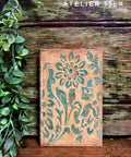 Belles and Whistles Tea Towel Floral - Stencil 
Textured copper/rusty canvas using Tea Towel Floral - Stencil  and Dixie Mud to give the stencil a raised effect painted in blue. Staged in front of damaged wooden wall with greenery.
