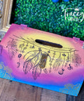 Belles and Whistles Western Boho - Silkscreen Stencil provides an extra decorative touch to any project!  A wooden box that has been chalk painted blue, pink and yellow sits on a wooden floor with a gold picture frame behind it.  The Western Boho Silkscreen Stencil has been applied with black and gold chalk paint.