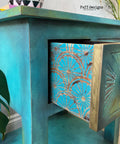 Belles and Whistles When Life Gives You Lemons - Stencil.  A blue chalk painted night stand with the drawer partially open.  The side of the drawer has the When Life Gives You Lemons stencil chalk painted in blue.  The knob on the drawer i bronze.  Greenery is on both the left and the right of the night stand.  A white & black chalk painted bowl sits on top of the night stand.