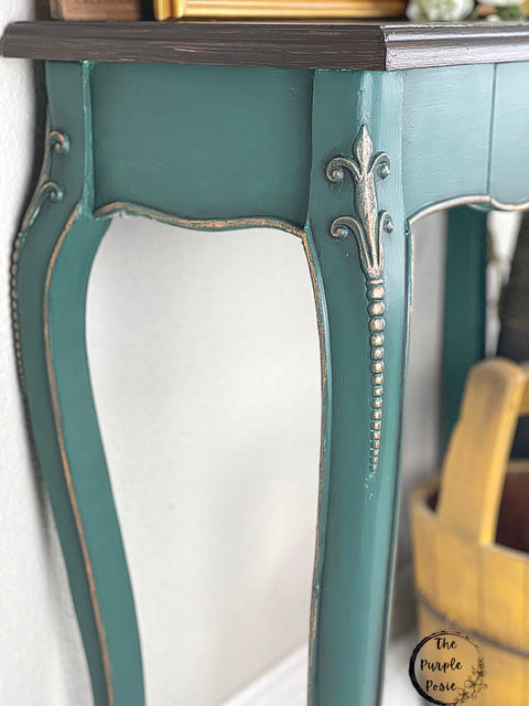 Dixie Belle Paint Black Glaze.
Image shows a pair of teal colored table legs with Black Glaze in the corners to give the piece depth and dimension and silver woodwork.