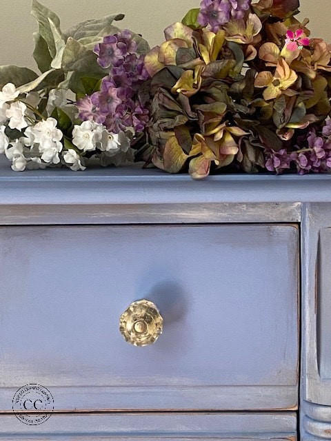 Dixie Belle Paint Blueberry Chalk Mineral Paint is the perfect paint for any DIY project!
Close up of dresser painted in Blueberry Chalk Mineral Paint with gold hardware and white distress detail around drawer.
