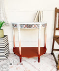 Dixie Belle Paint Buttercream Chalk Mineral Paint is the perfect paint for any DIY project!
Console table with  Buttercream Chalk Mineral Paint fading into a copper red color with the Whimsical Mediterranean - Rice Decoupage Paper on the drawer and around the trim. Staged with books on the top and on the left side.