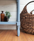 Dixie Belle Paint Dusty Blue Chalk Mineral Paint is the perfect paint for any DIY project! Blue chalk painted furniture makeover. Staged with small glass vases with greenery and a large woven basket next to the furniture on a wooden floor.