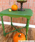 Dixie Belle Paint Evergreen Chalk Mineral Paint is the perfect paint for any DIY project! Green painted table with a dark wash. Two very small and one medium pumpkins on top next to a brown cake stand holding more small pumpkins. One large pumpkin placed underneath the table.