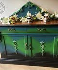 Dixie Belle Paint Evergreen Chalk Mineral Paint is the perfect paint for any DIY project! Green, blue, and black painted buffet with a medium stained top. Styled with faux white lilies on top along with 3 skulls, one is gold, one is black and white checkered, and one is silver.
