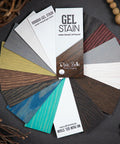 Dixie Belle Paint Gel Stain Fan Deck.  Displays all the colors of both lines of Gel stains, Deck is fanned out with cards that read " Gel Stain water based - oiled based Dixie Belle Paint Company" " VOODOO GEL STAIN water based gel stain" " No Pain Gel Stain Oil Based stain". Hold different color cards next to the piece of furniture you'd like to give a makeover! Staged around fanned out deck is wooden beads and twigs.