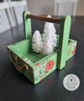Dixie Belle Paint Kudzu Chalk Mineral Paint is the perfect paint for any DIY project!
Miniature tray with handle painted in Kudzu Chalk Mineral Paint with white and red flowers pattern on the piece. Staged inside the tray is 3 white miniature christmas tree.