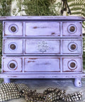Dixie Belle Paint Lucky Lavender Chalk Mineral Paint is the perfect paint for any DIY project!
Distressed dresser painted in Lucky Lavender CMP with bronze hardware. Staged with greenery around piece.