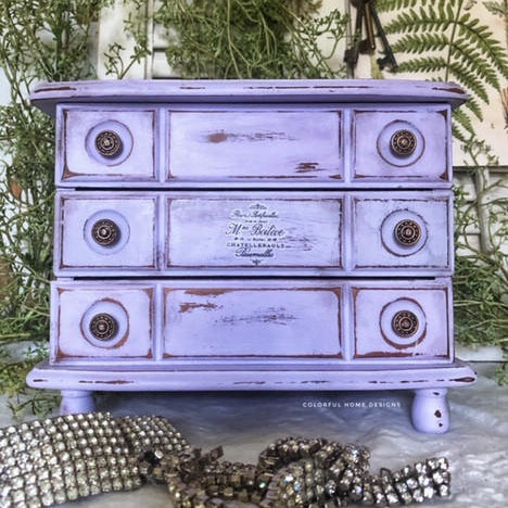 Dixie Belle Paint Lucky Lavender Chalk Mineral Paint is the perfect paint for any DIY project!
Distressed dresser painted in Lucky Lavender CMP with bronze hardware. Staged with greenery around piece.
