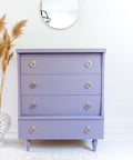 Dixie Belle Paint Lucky Lavender Chalk Mineral Paint is the perfect paint for any DIY project!
Beautiful white minimalistic stage with a dresser painted in Lucky Lavender Chalk Mineral Paint and gold hardware
