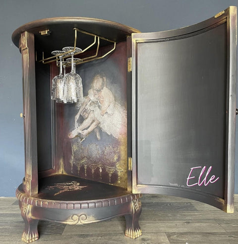 Dixie Belle Paint Manatee Gray Chalk Mineral Paint is the perfect paint for any DIY project! Chalk Painted dark Gray, Red and Gold and Black Wine Cabinet with a Ballerina Decoupage Tissue Paper. Staged with glass wine glasses inside.