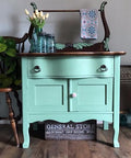 Dixie Belle Paint Mint Julep Chalk Mineral Paint is the perfect paint for any DIY project! Mint green Chalk Mineral painted washstand with a white knob and dark hard ware, and a dark wood stained  top with. Staged with three glass mason Jars and white tulips inside, and a pretty colorful towel on the rack.
