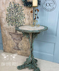 Dixie Belle Paint Patina Spray. Metal table Painted and sprayed with Patina to look rusty. Staged in front of a Blue door.