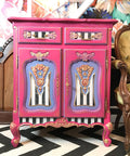 Dixie Belle Paint Peony Chalk Mineral Paint is the perfect paint for any DIY project! Pink chalk painted end table with black and white stripes on the front and light purple painted on the doors.
