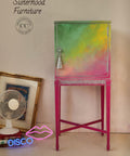 Dixie Belle Paint Peony Chalk Mineral Paint is the perfect paint for any DIY project! Pink, yellow and green chalk painted Ombre tall end table cabinet Staged next to neon signs and a fan.