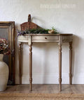 Dixie Belle Paint Putty Chalk Mineral Paint is the perfect paint for any DIY project! A half moon hallway table in a neutral tone paint with lavender staged on top with a big vase and picture frame to the left of the table.