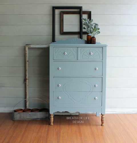 Dixie Belle Paint Savannah Mist Chalk Mineral Paint is the perfect paint for any DIY project! A tall dresser that is painted in the light blue color, savannah mist. This dresser has 2 small drawers on top and 3 long drawers towards the bottom.
