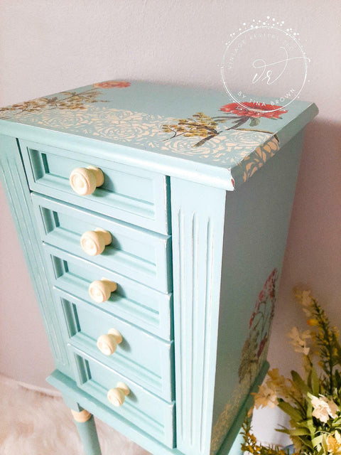 Dixie Belle Paint Sea Glass Chalk Mineral Paint is the perfect paint for any DIY project! A tall jewelry box painted in sea glass and wooden white hardware. There is a stencil in white on the top and a flower transfer on top of the jewelry box.
