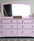 Dixie Belle Paint Soft Pink Chalk Mineral Paint is the perfect paint for any DIY project! A dresser with a mirror on top that is painted in soft pink chalk mineral paint and staged with home decor items.