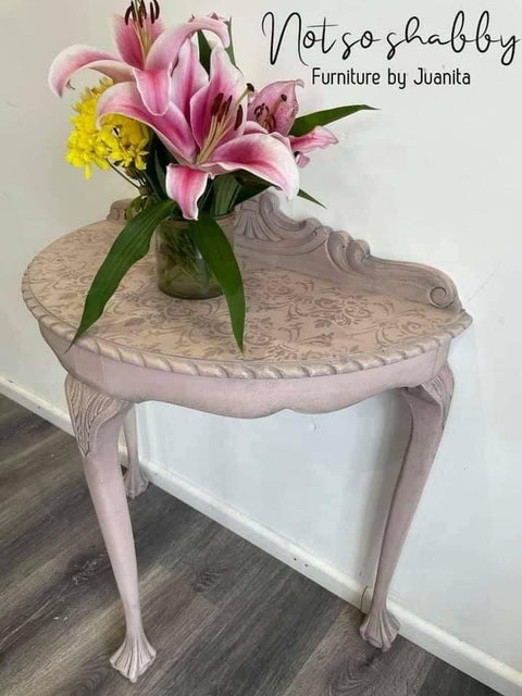 Dixie Belle Paint Soft Pink Chalk Mineral Paint is the perfect paint for any DIY project! A half-moon hallway table painted in soft pink chalk mineral paint and is accompanied with a stencil on the top. This hallway table is staged with flowers on the top of the table.