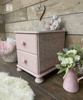 Dixie Belle Paint Soft Pink Chalk Mineral Paint is the perfect paint for any DIY project! A small side table with 2 drawers painted in the soft pink chalk mineral paint and is accompanied  by a stencil on the sides and is staged with plants on the right and other household decor items.