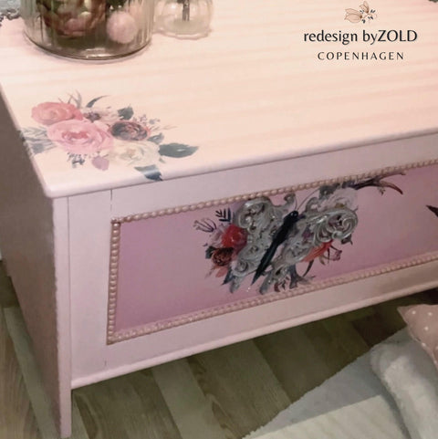 Dixie Belle Paint Soft Pink Chalk Mineral Paint is the perfect paint for any DIY project! A coffee table painted in the soft pink chalk mineral paint and is accompanied by a flower stencil on the front drawer and top of the table.