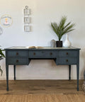 Dixie Belle Paint Stormy Seas Chalk Mineral Paint is the perfect paint for any DIY project!
Office desk painted in Stormy Seas Chalk Mineral Paint with bronze hardware. Staged with different pottery and greenery.