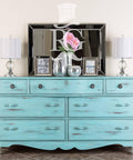 Dixie Belle Paint The Gulf Chalk Mineral Paint dresser that is distressed and has two white lamps on the top