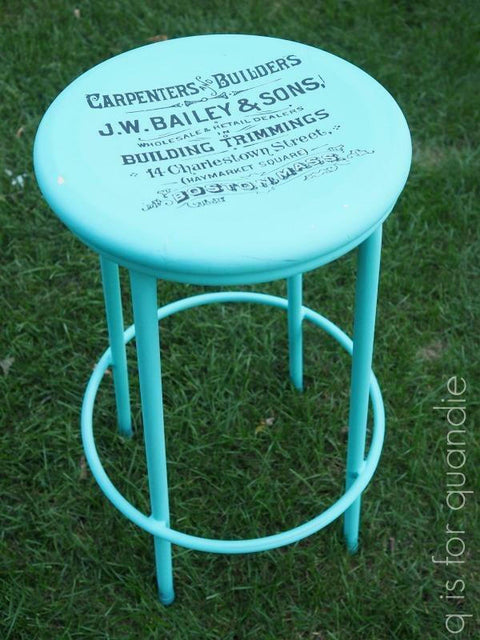 Dixie Belle Paint The Gulf Chalk Mineral Paint is the perfect paint for any DIY project! A blue chalk painted barstool with  letters stenciled on in black paint, sitting in a grassy area.