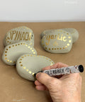 Hand writing on rocks with a gold marker, labeled 'Spinach' and 'Garlic'.