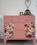 Pink dresser with floral design in a room setting with decor elements.